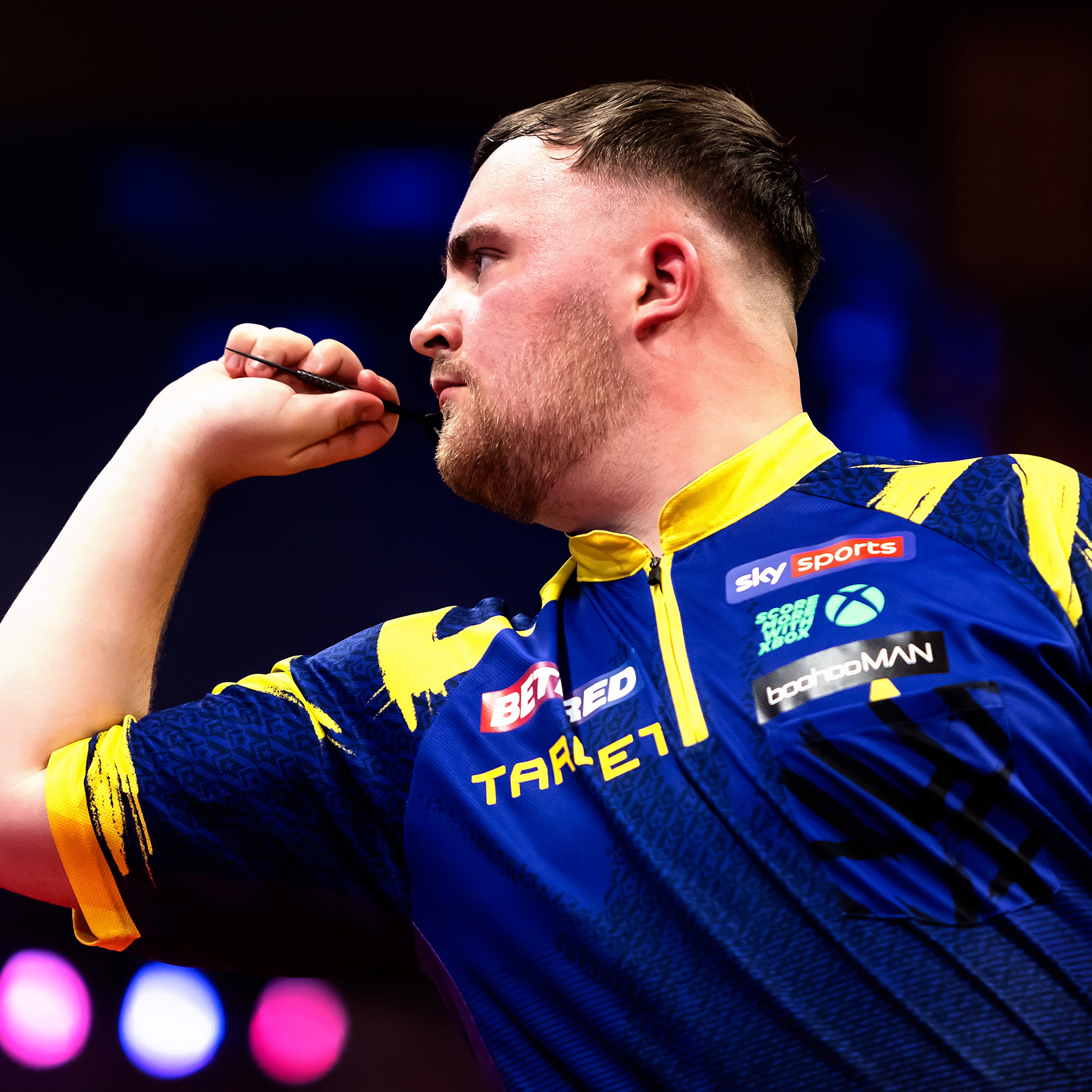 Luke Littler Darts professional throwing on stage during competition with his own set of darts